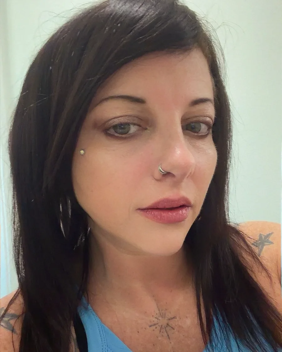 Portrait of Sarah, a professional hair stylist with long dark hair, looking toward the camera.