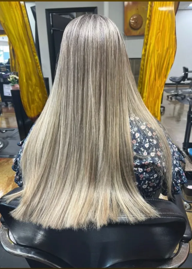 Long cool blonde hair with a smooth finish and darker root dimension.