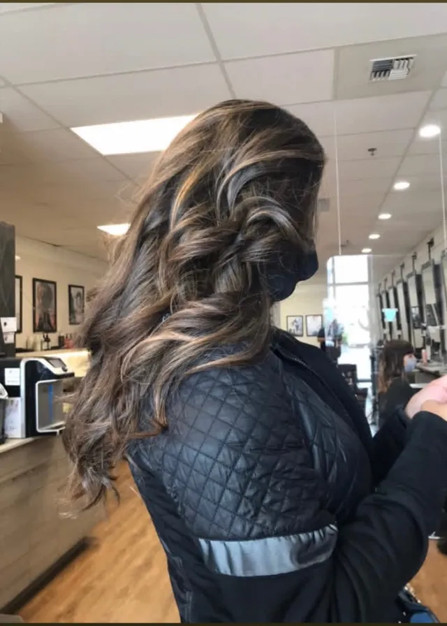 Dark brunette hair with warm dimensional highlights and volume.